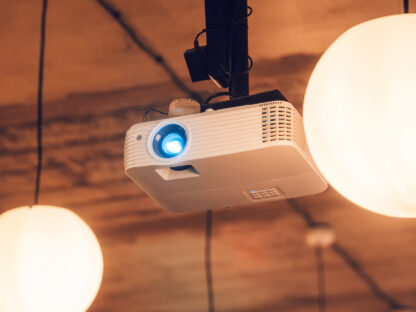 Ceiling-mounted projector with a blue light beam, surrounded by two round pendant lights.