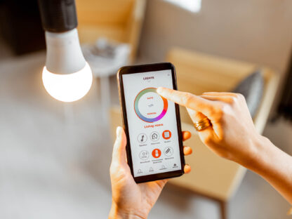 Person using a smartphone app to control a living room light. The interface shows brightness and on/off options.