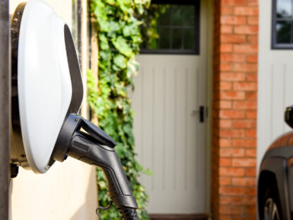 Premium EV Outlet plugged into the wall of a house to charge an electric car.