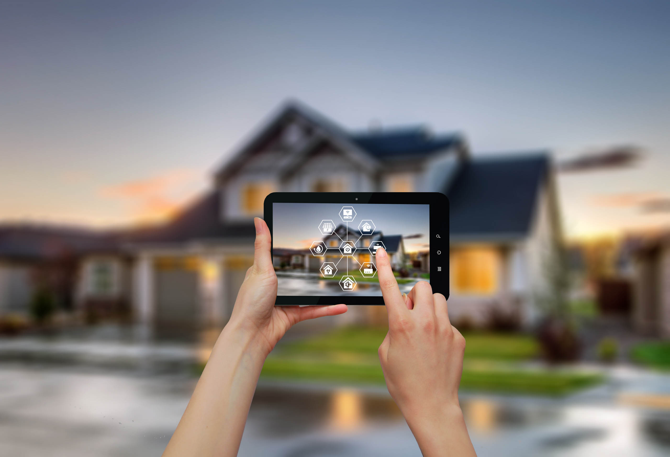 Person using a tablet to control smart home automation features, with a modern house in the background.