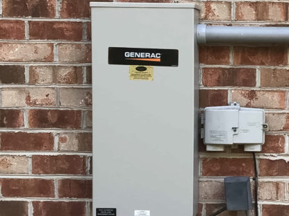 Outdoor Generac electrical panel mounted on a brick wall, with conduits and nearby utility boxes.