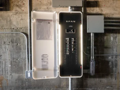 An open electrical panel attached to a wall with labeled switches and wiring visible.