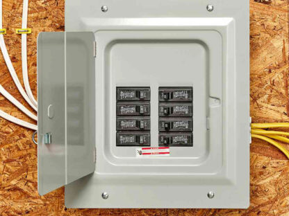 An open electrical panel with circuit breakers mounted on a plywood wall, showing wires entering from the top and right side.