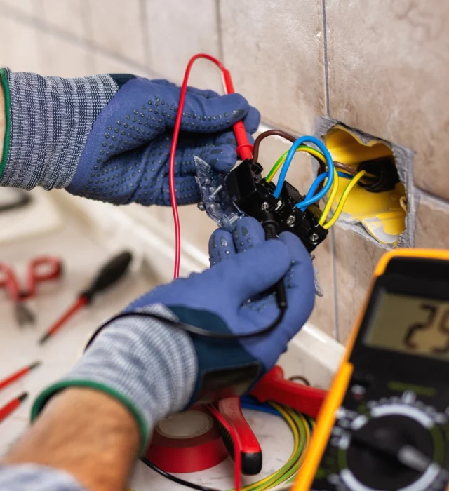 A residential electrician doing repair work on a kitchen outlet.