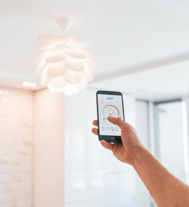 a college station electrician using a smart home automation app to turn on overhead lighting in a home