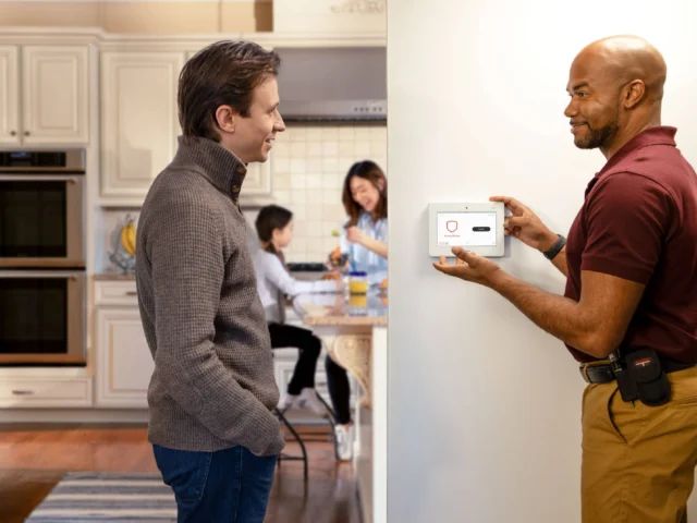 Dad speaking with a home security service technician in Texas who is explaining a newly installed home security system.